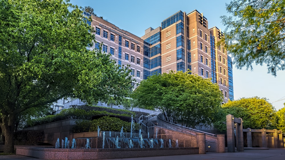 brown concrete building near green trees under blue sky during daytime