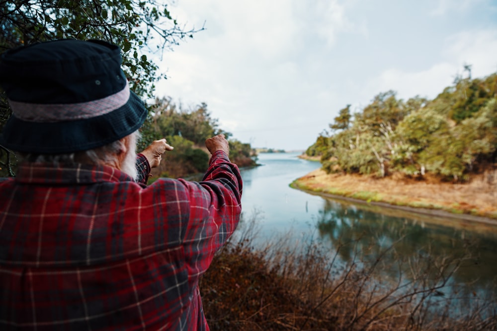 homem em vermelho e camisa xadrez xadrez tirando foto do lago durante o dia