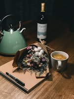 A smiling woman journaling with a cup of herbal tea on a sand-colored wooden table.