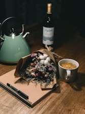 Close-up of a journal and pen resting on a white linen cloth beside a cup of herbal tea.