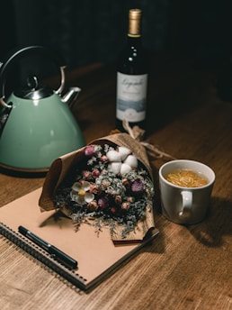 A person journaling with a cup of tea beside them on a wooden table