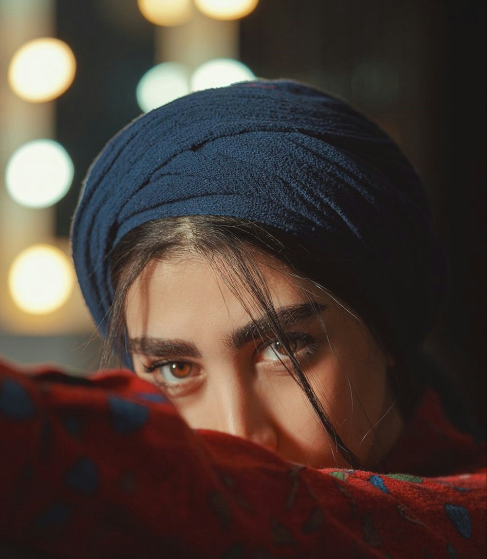 woman in red scarf wearing black knit cap