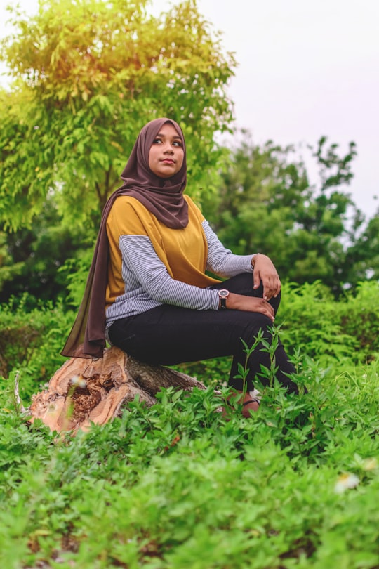 woman in yellow hijab sitting on brown log in Kulhudhuffushi Maldives