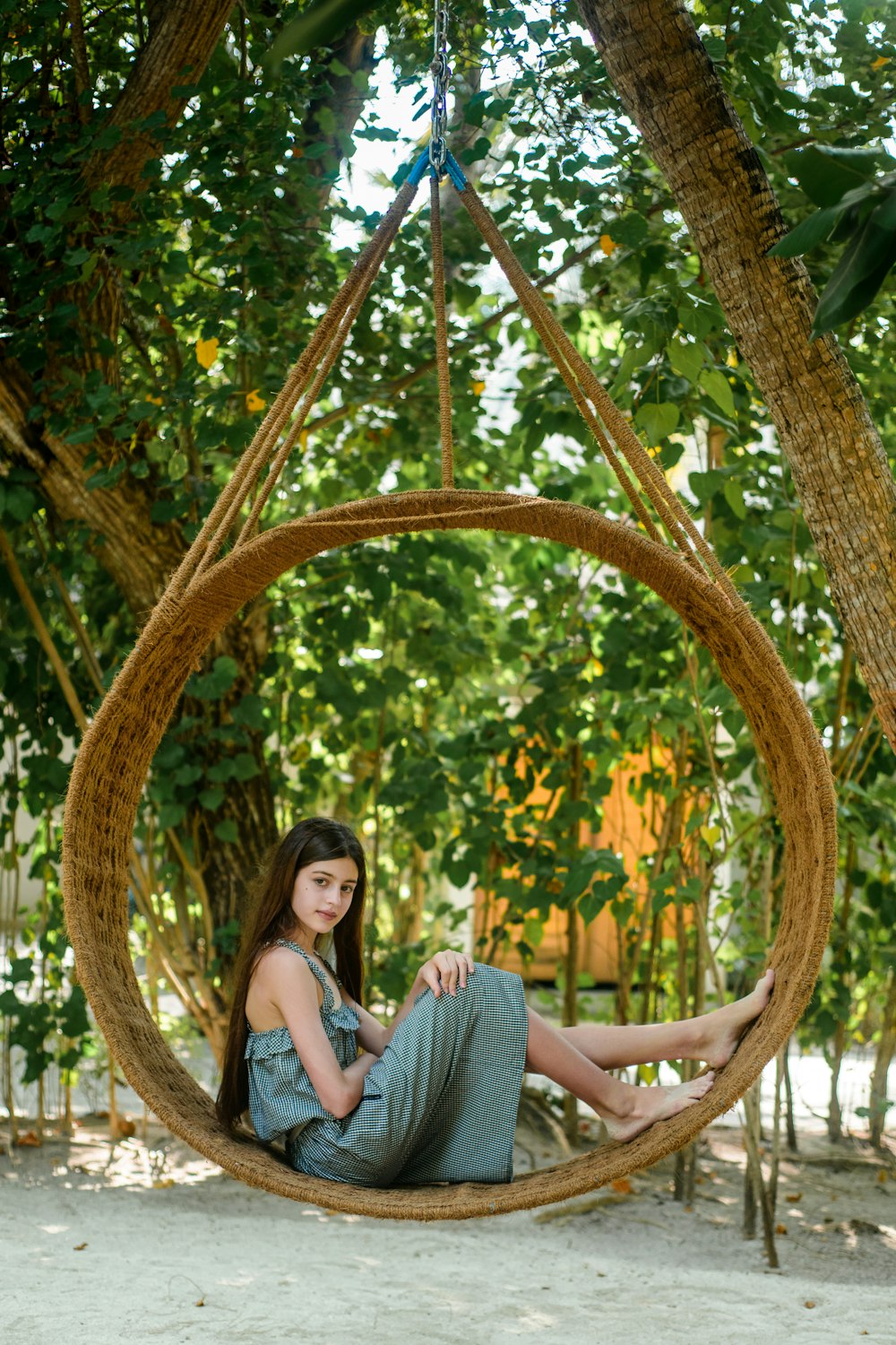 woman in gray dress sitting on brown wooden swing