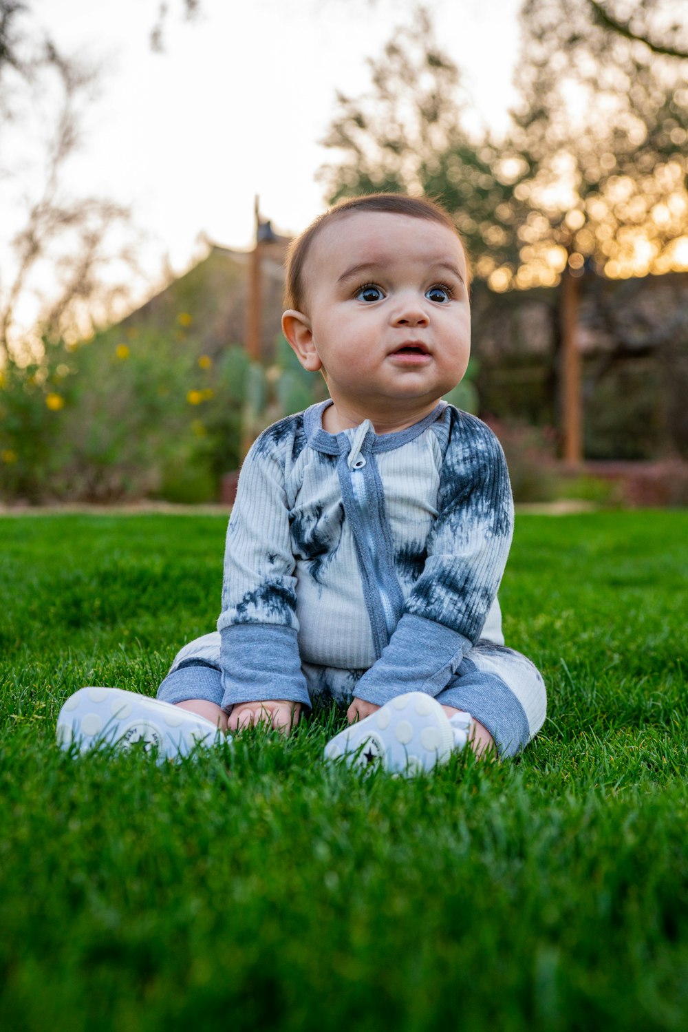 baby in gray sweater sitting on green grass field during daytime