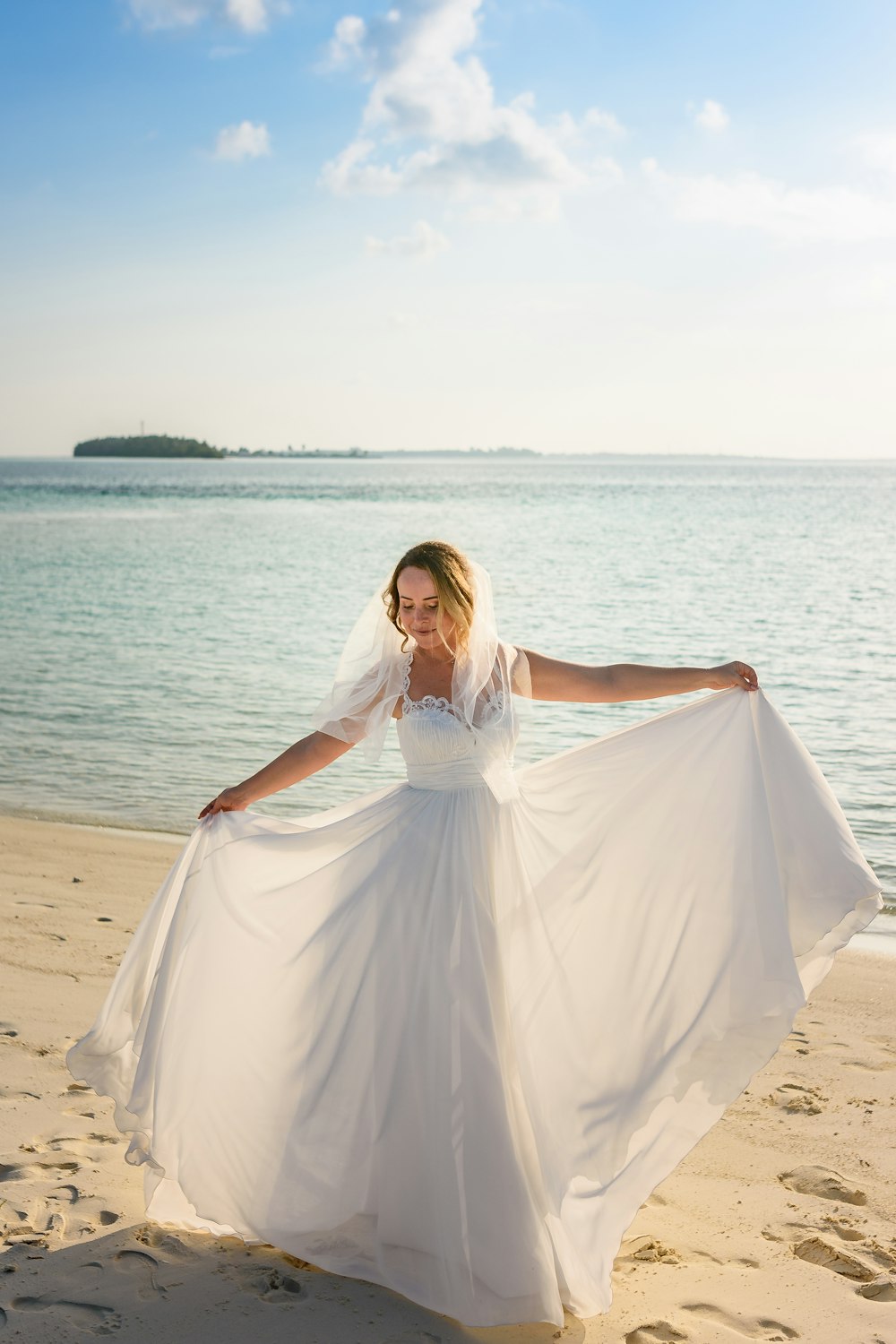 Mujer con vestido blanco de pie en la playa durante el día