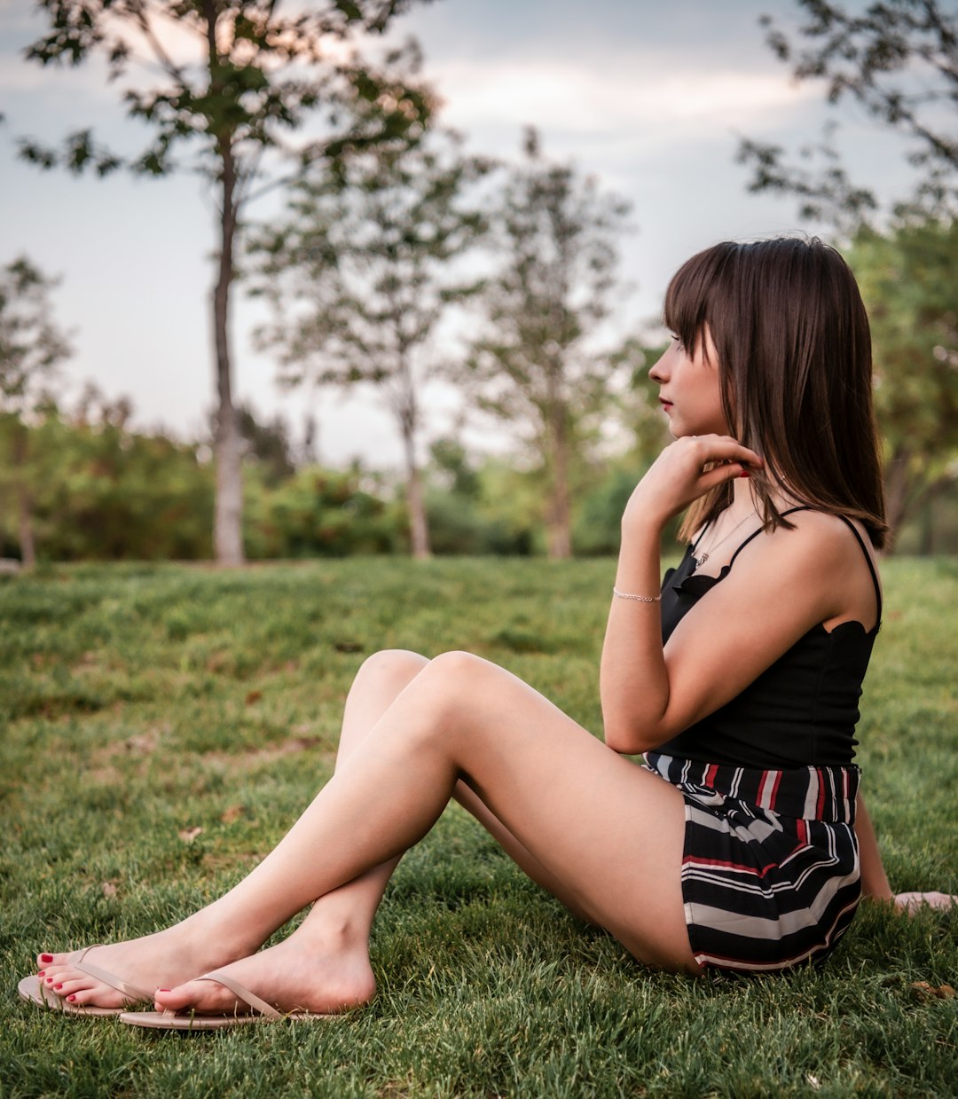 woman in black tank top and black and white striped skirt sitting on green grass during