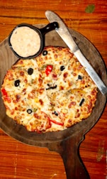 A rustic wooden board displaying both Roman pizza slices and a small bowl of dipping sauce.