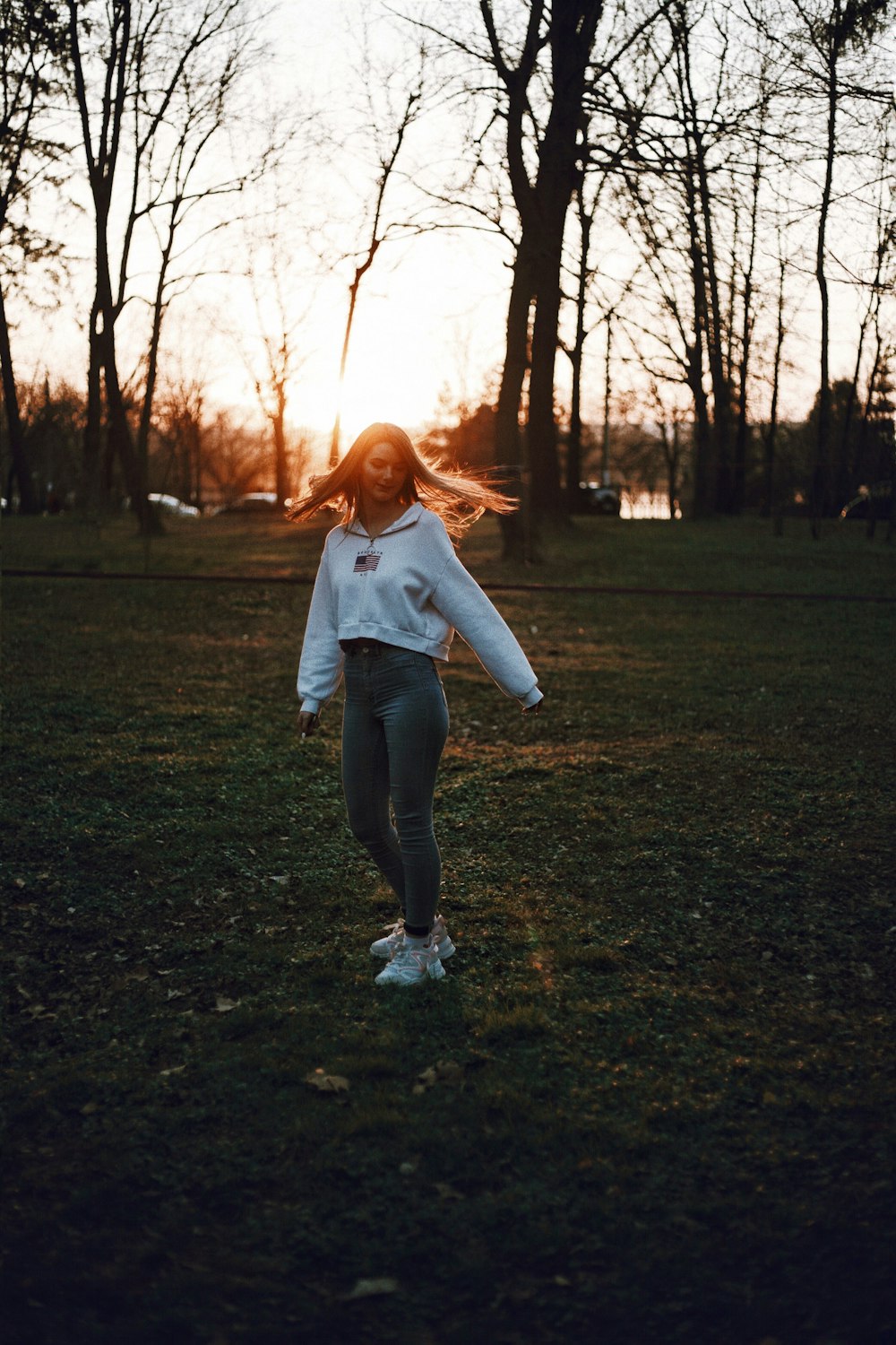 woman in white long sleeve shirt and blue denim jeans standing on green grass field during