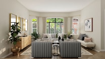 A well-furnished living room with a modern, minimalist aesthetic. The space features a large window framed by light curtains, allowing natural light to flood the room. There is a gray tufted sofa set, a wooden sideboard, several potted plants, and a large framed artwork on the wall. The color palette is neutral with green and wooden accents.