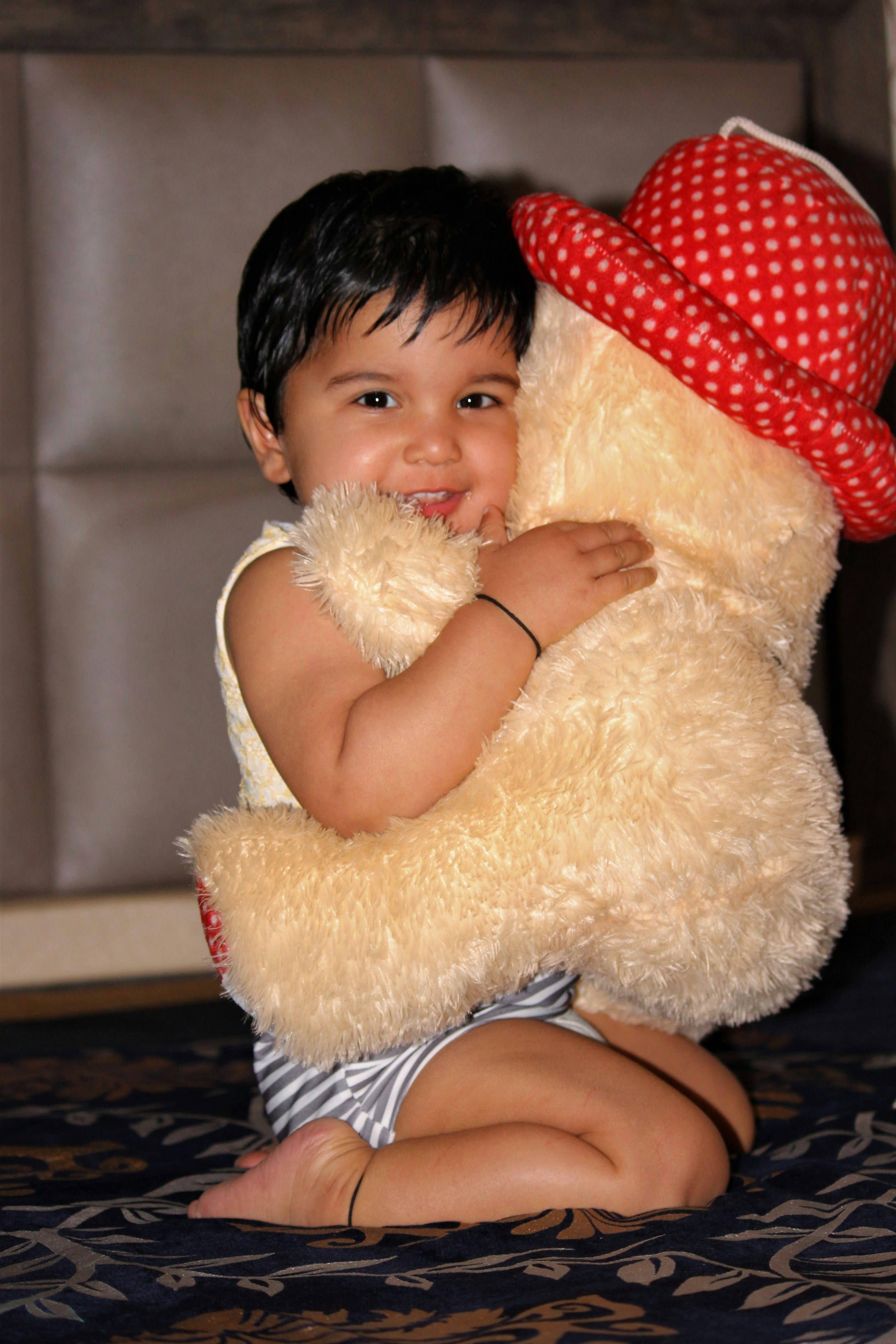 Young child holding soft plush teddy bear and smiling