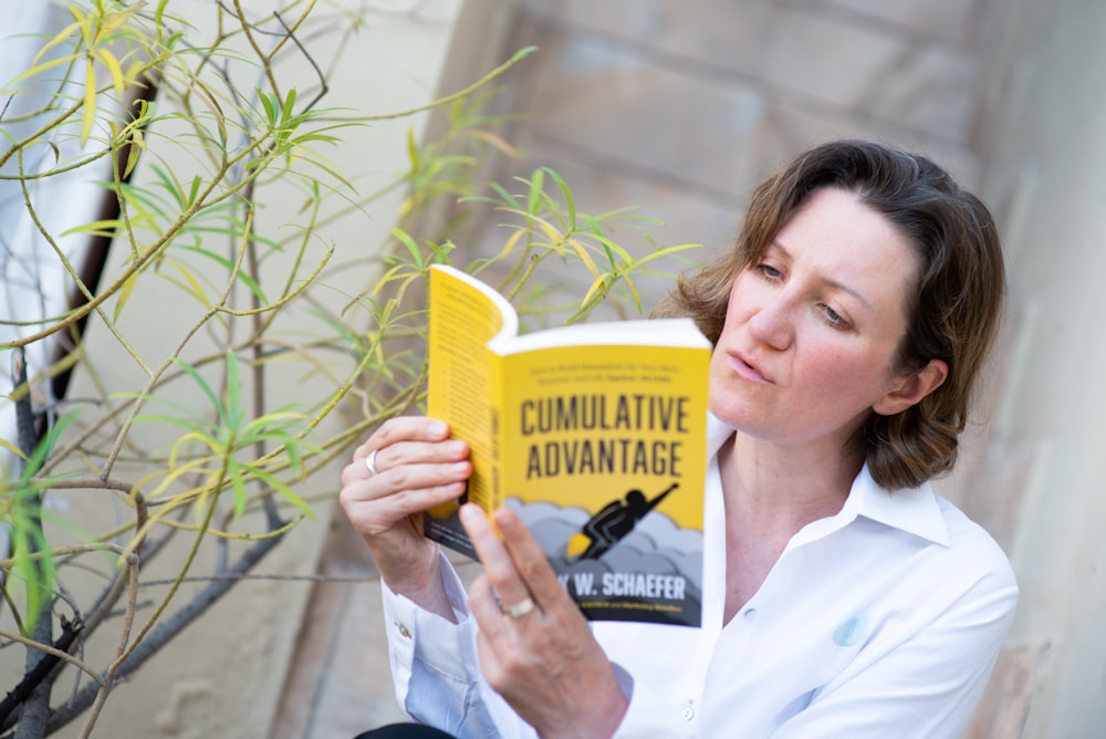woman in white button up shirt holding yellow book
