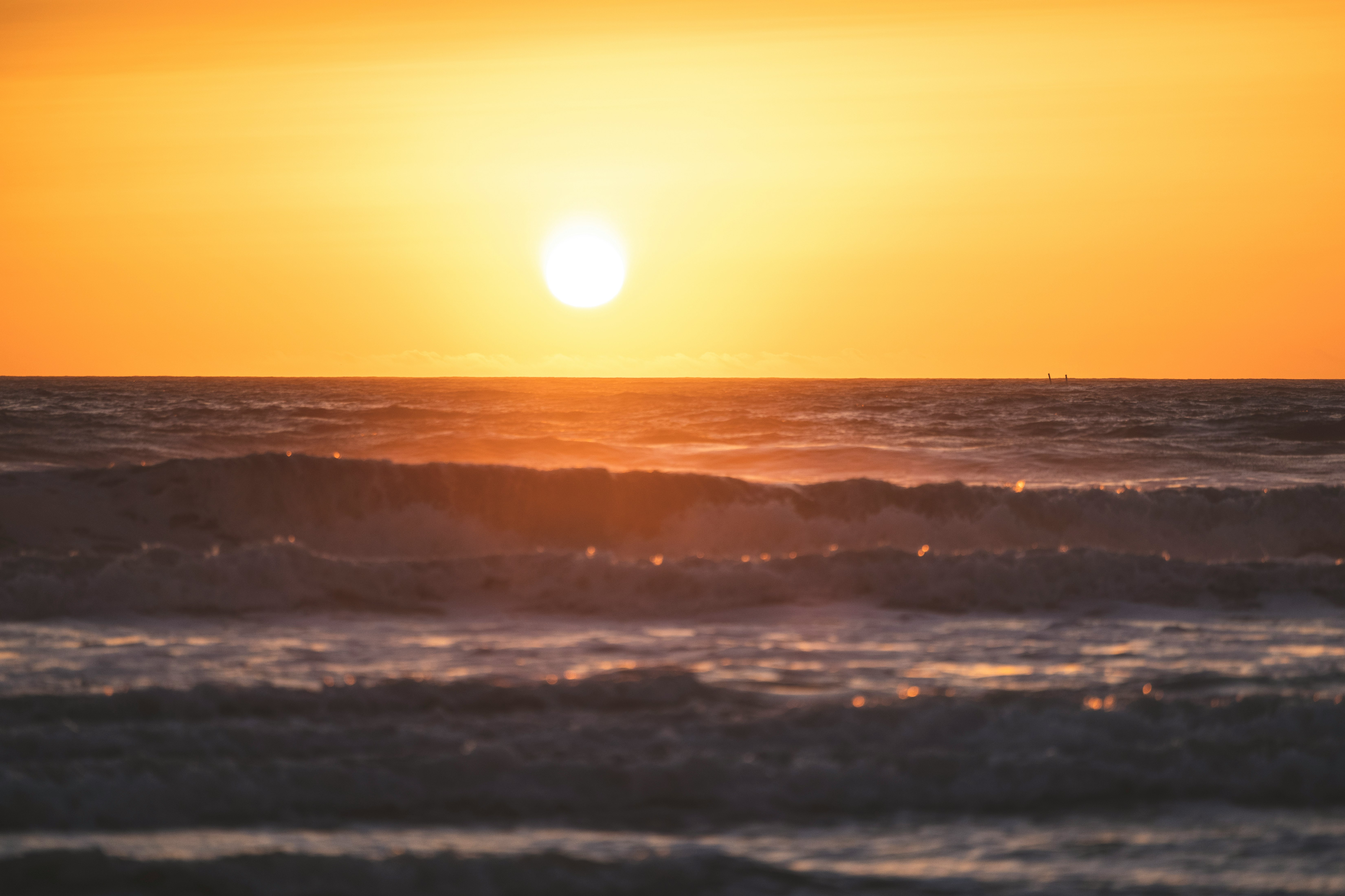 ocean waves crashing on shore during sunset