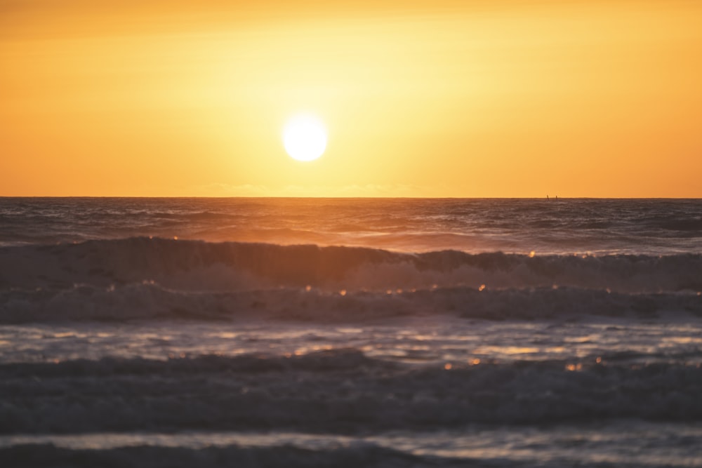 ocean waves crashing on shore during sunset