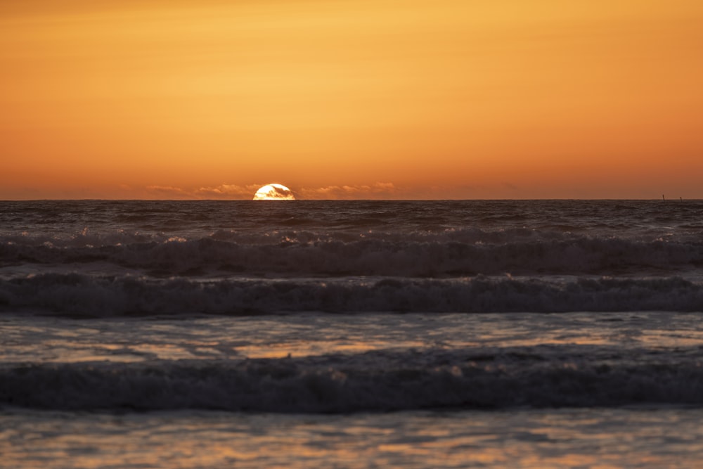 ocean waves crashing on shore during sunset