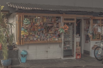 A cozy boutique corner showcasing colorful snack packages, vibrant shirts, and an array of spicy sauces on wooden shelves.
