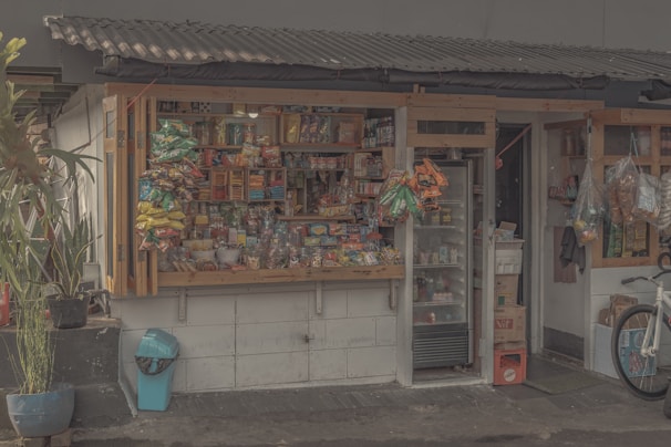 A cozy neighborhood minimarket with shelves stocked with beverages and groceries.
