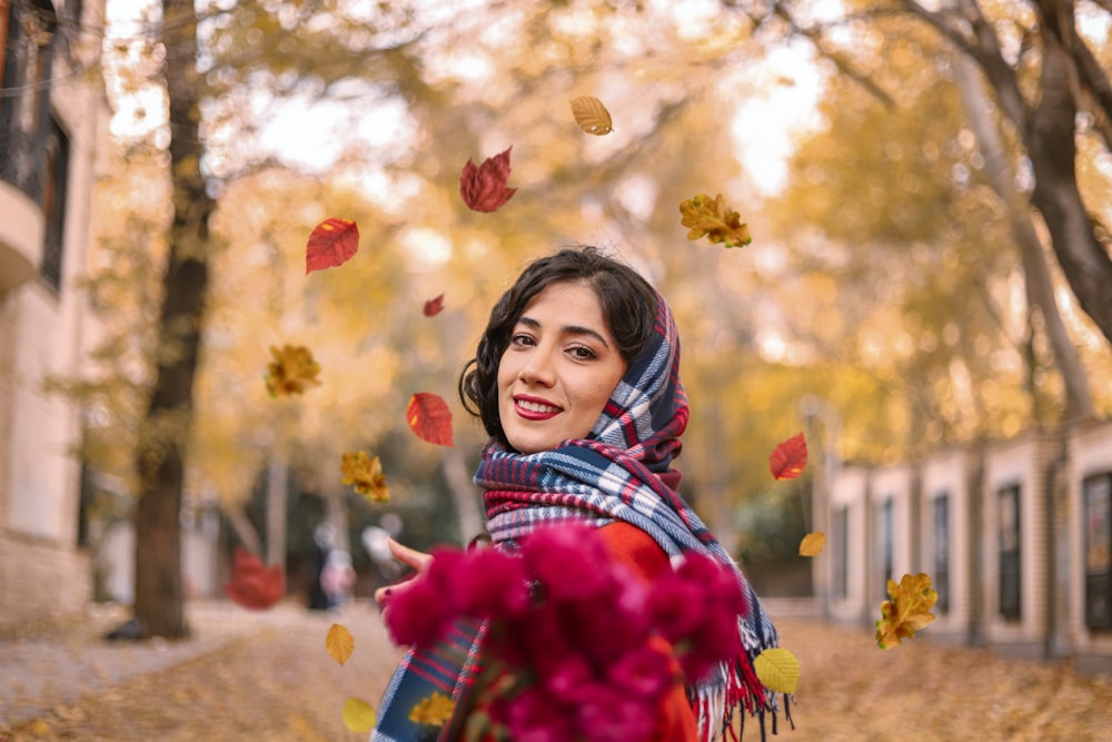 girl in red and white plaid scarf standing under red flowers
