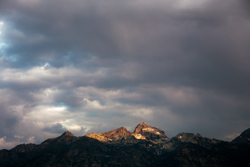 brown and black mountains under gray clouds