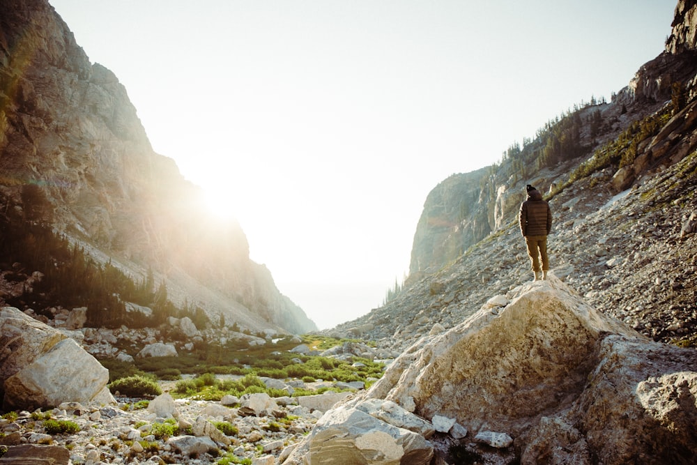 woman in black jacket and brown pants standing on rocky mountain during daytime