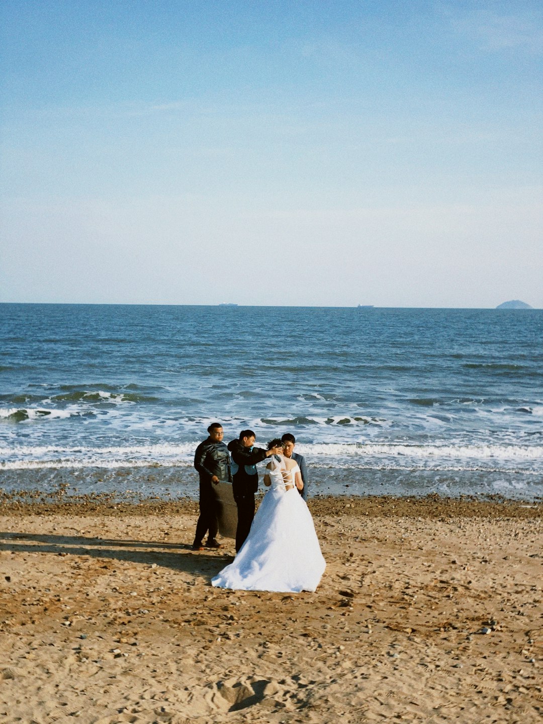 bride and groom standing on beach during daytime