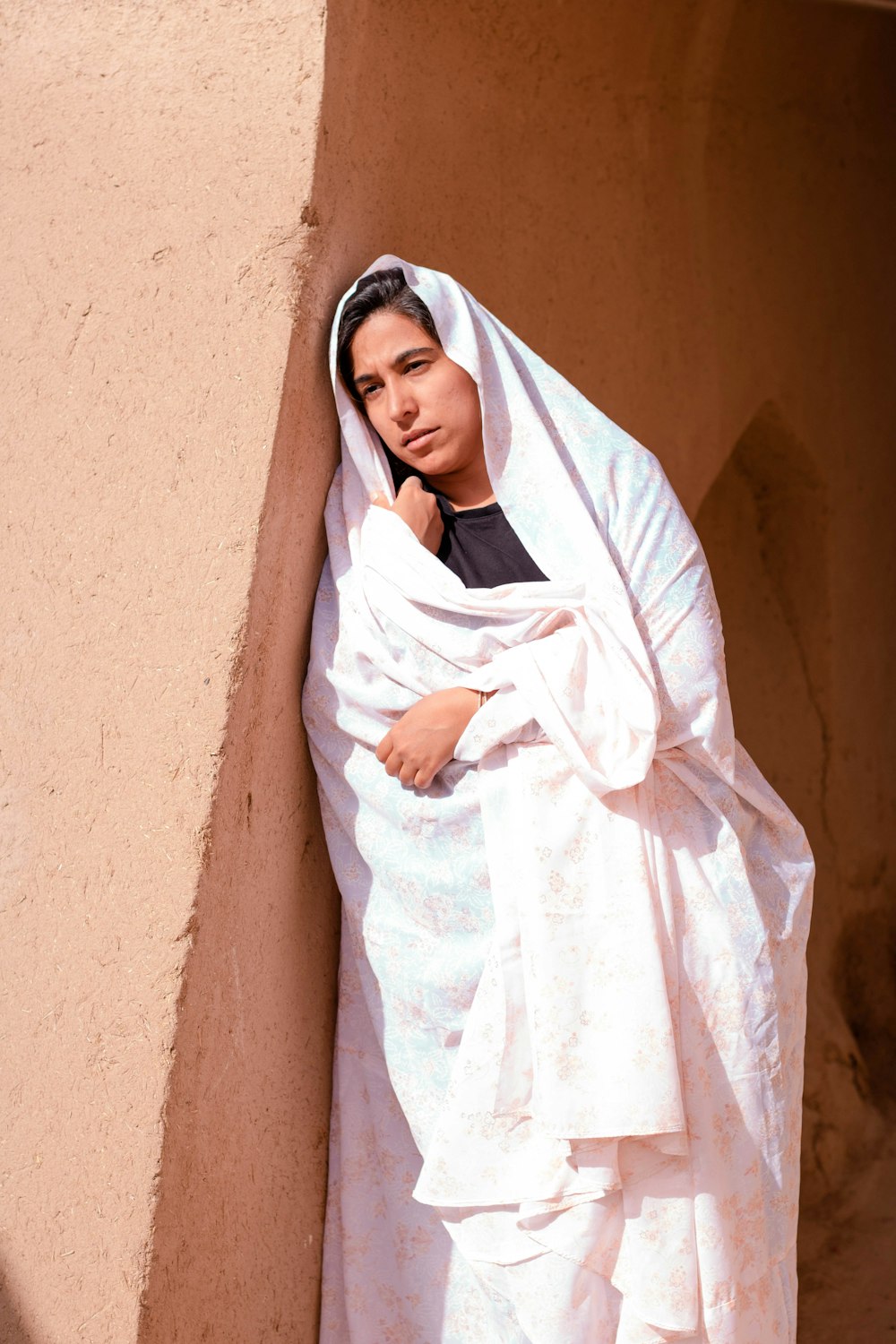 woman in white hijab standing beside brown wall