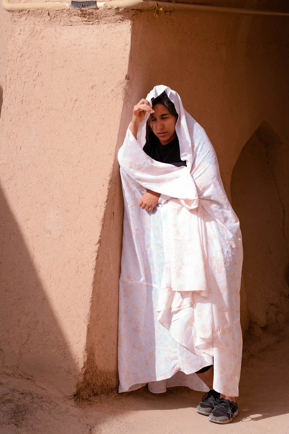 woman in white hijab standing beside brown wall