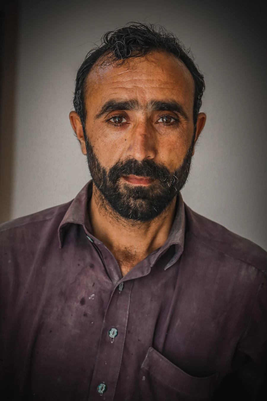 Mature bearded man in a black button-up shirt, professional portrait.