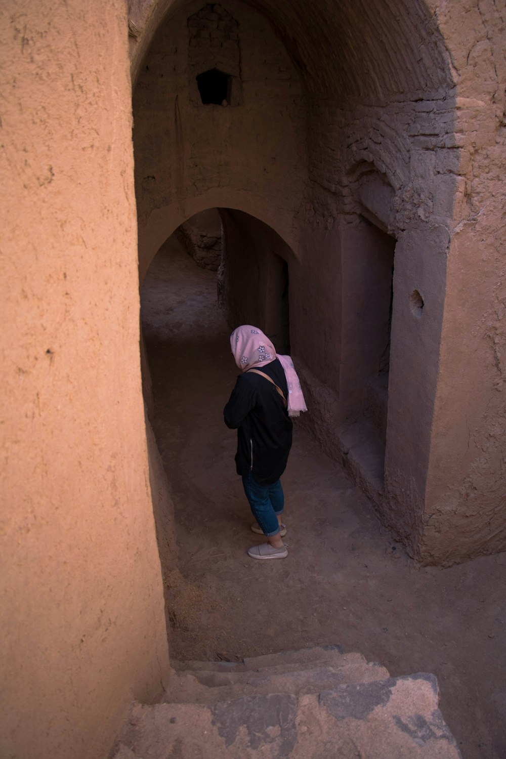 girl in pink hijab standing on brown concrete tunnel during daytime