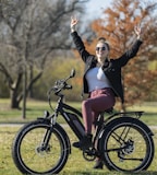 woman in black jacket and pink skirt riding on black bicycle during daytime
