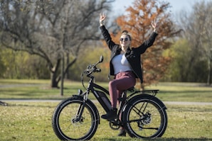woman in black jacket and pink skirt riding on black bicycle during daytime