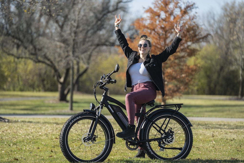 woman in black jacket and pink skirt riding on black bicycle during daytime