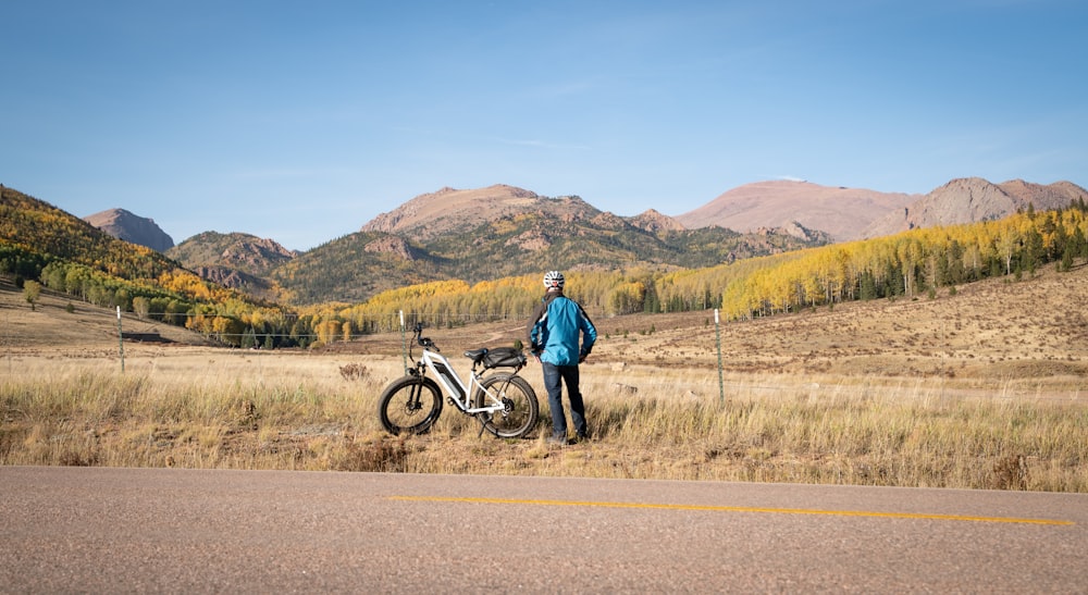 man in blue jacket and blue denim jeans riding on black motorcycle on road during daytime