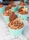 A display of assorted cupcakes in chocolate brown and champagne gold wrappers, topped with artistic frosting swirls.