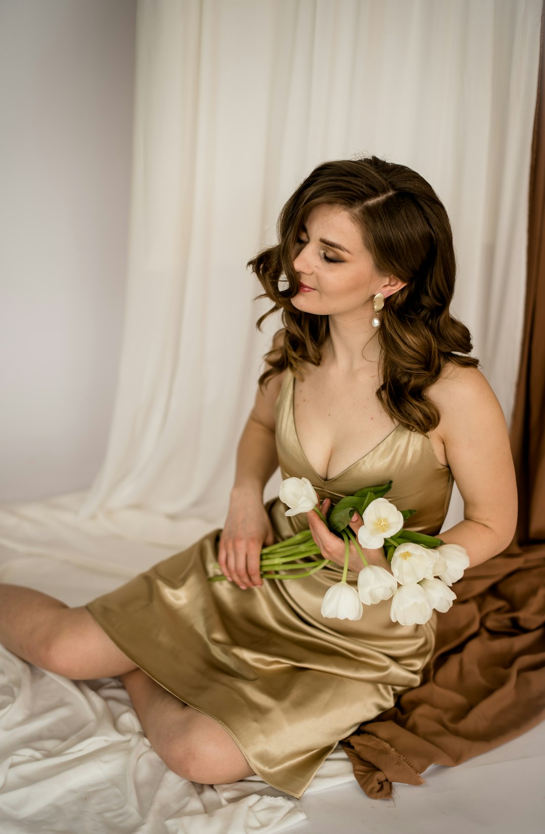 woman in beige spaghetti strap dress holding white rose bouquet