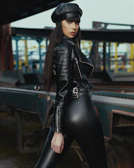 A sleek black leather military-style beret styled with a leather jacket on an urban street.