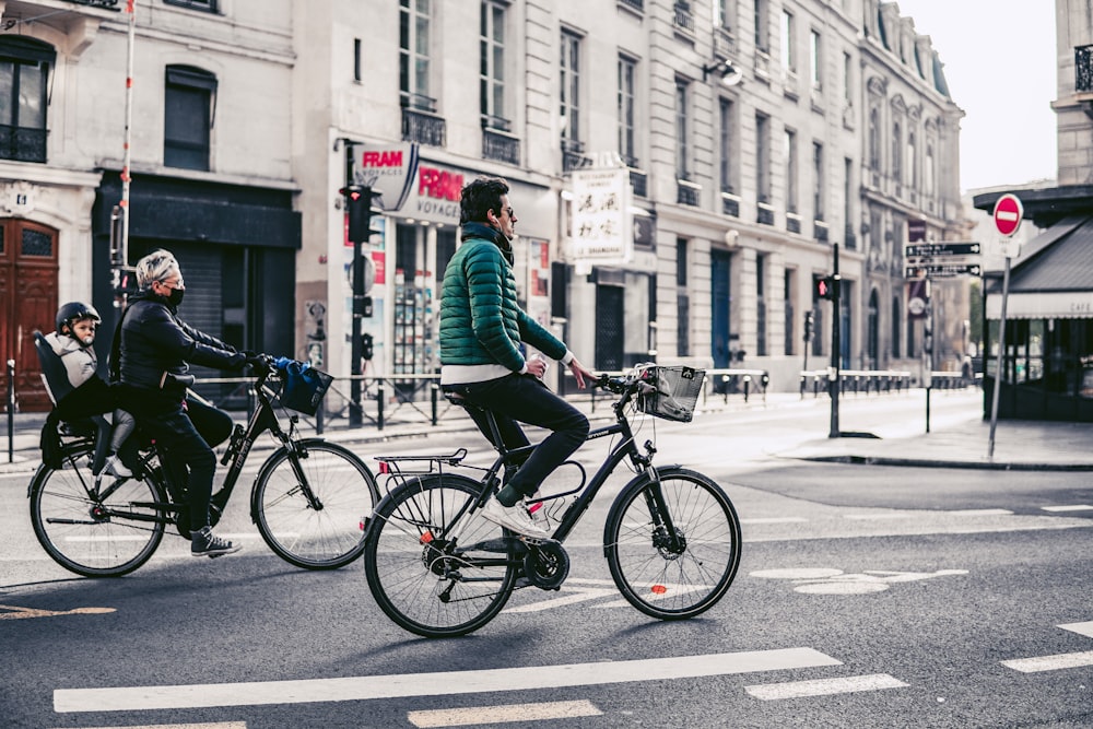 man in green jacket riding on black bicycle on road during daytime