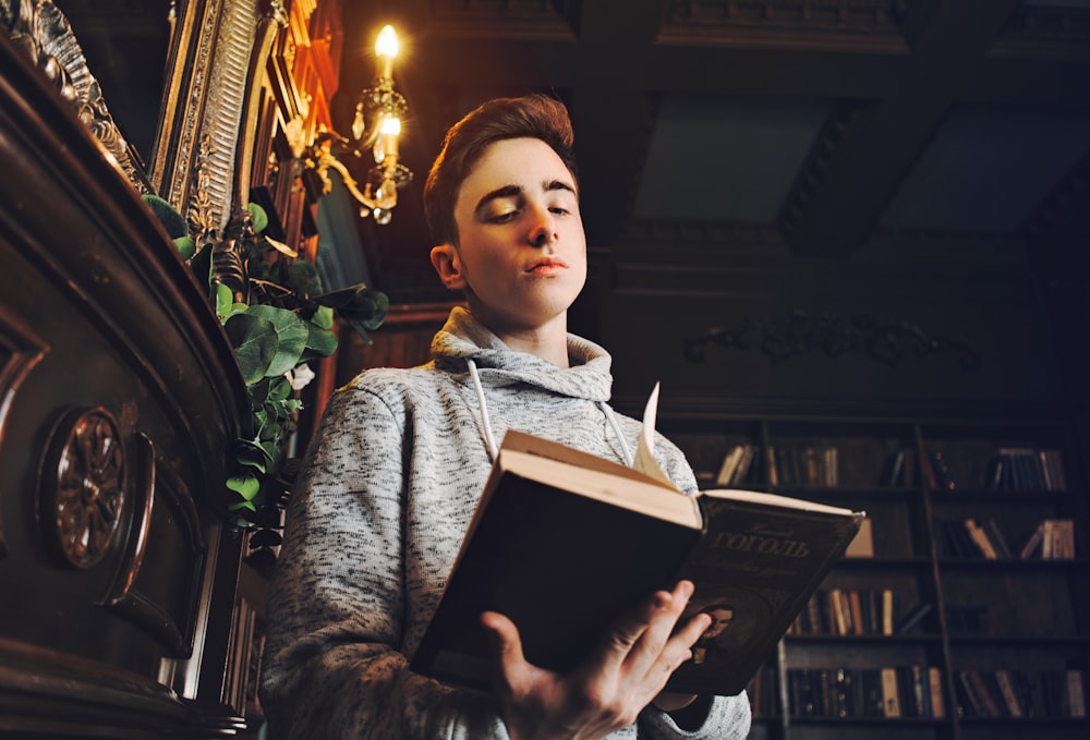 woman in gray sweater holding book