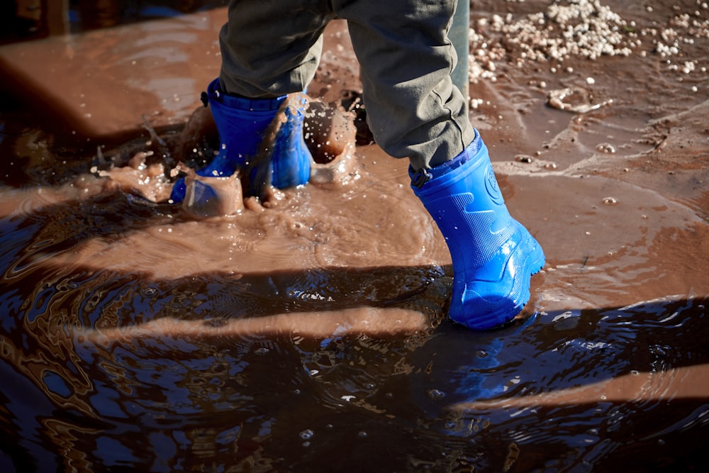 person in blue rain boots standing on water