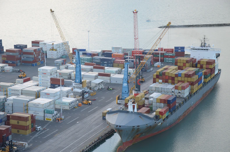 Cargo containers being loaded at a busy port in Pakistan.