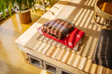 A vibrant, patterned blanket folded neatly on a sleek wooden bench.