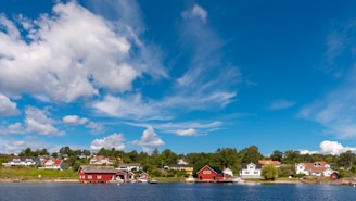 red and white house near body of water under blue sky during daytime