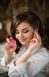woman in white shirt holding red round fruit