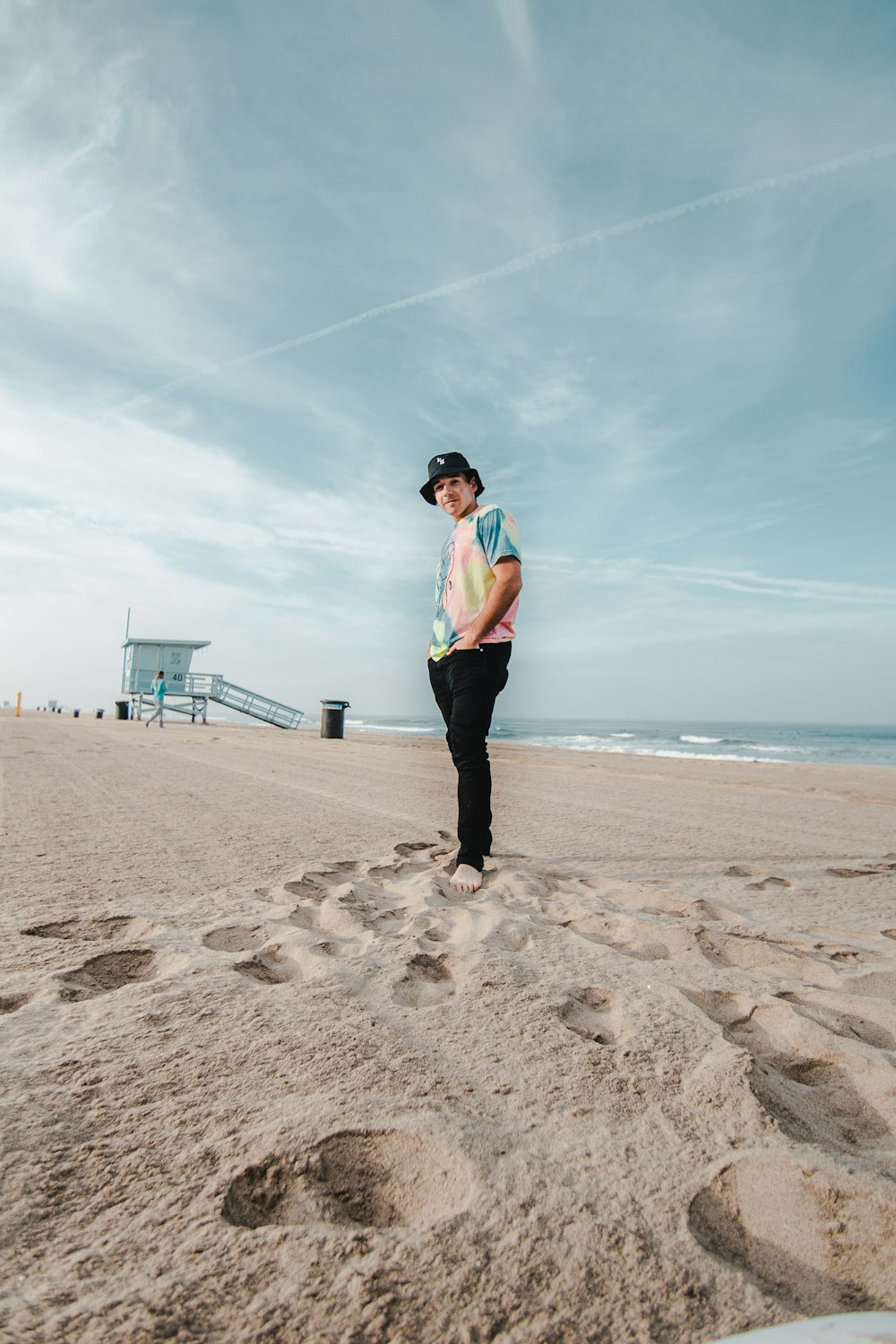 man in blue dress shirt and black pants standing on beach shore during daytime