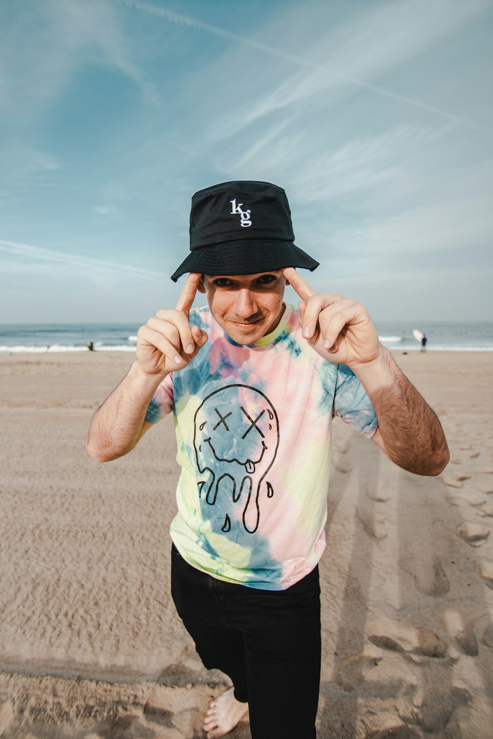 man in blue crew neck t-shirt and black fitted cap standing on beach during daytime