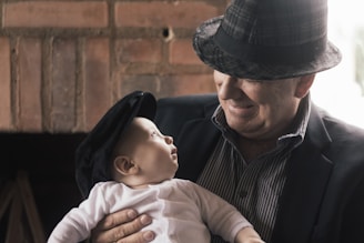 man in black and white striped shirt carrying baby