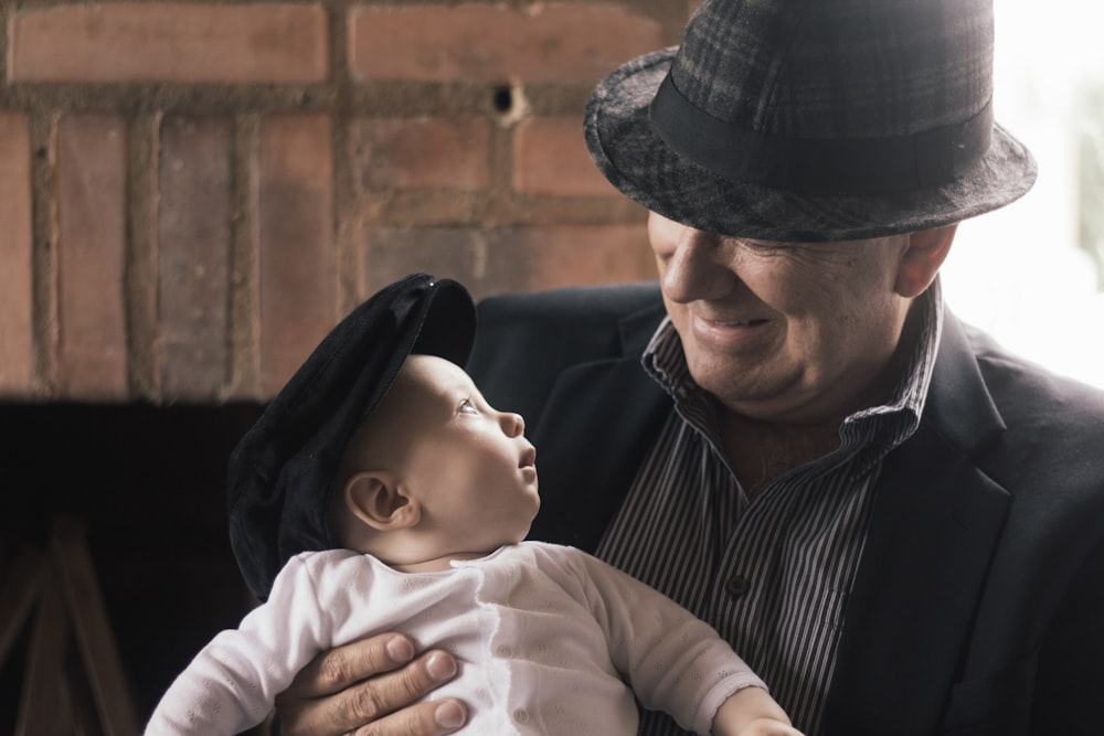 homme en chemise rayée noire et blanche portant bébé