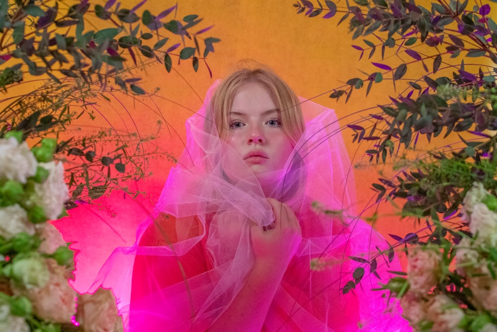 girl in pink dress standing beside brown leaves