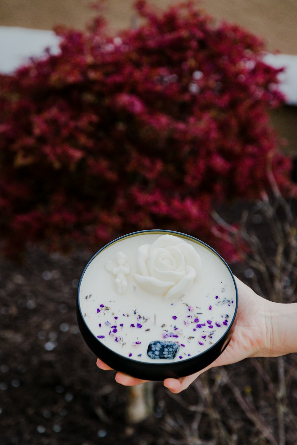 person holding white and purple floral round cup