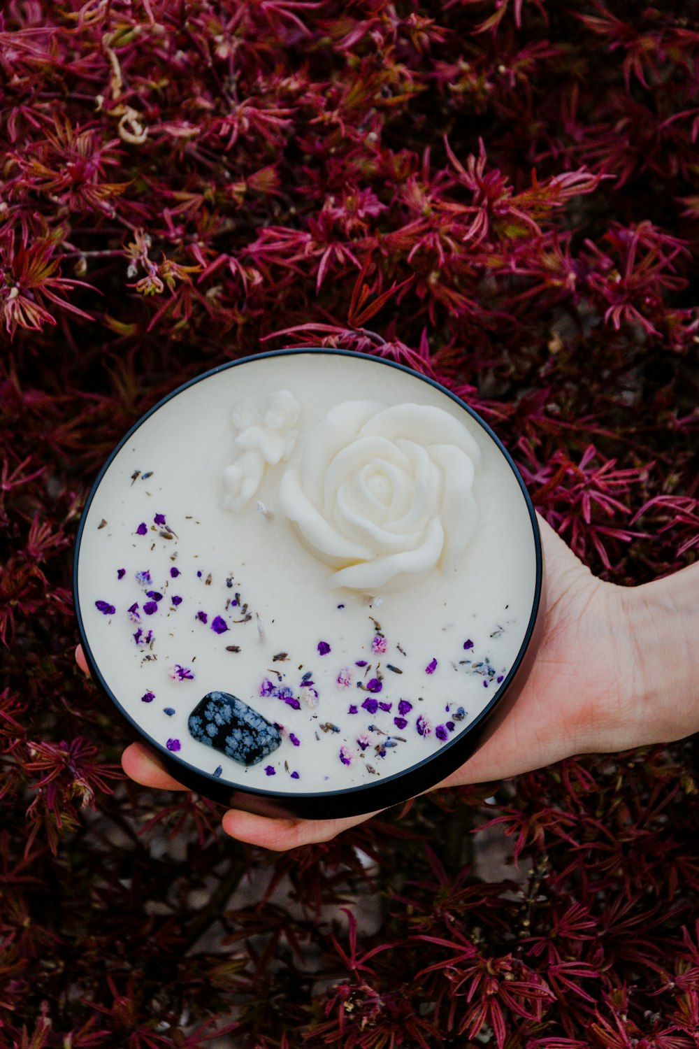 person holding white cream on white and blue floral ceramic plate